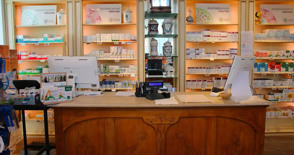 Il banco storico in legno della Farmacia Calderara con gli scaffali dei prodotti